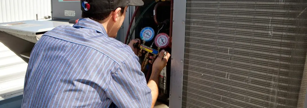 HVAC technician servicing a condenser unit in Schoolcraft